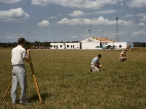man in white t-shirt and black shorts sitting on green grass field during daytime