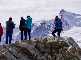 group of people standing on gray rock formation during daytime